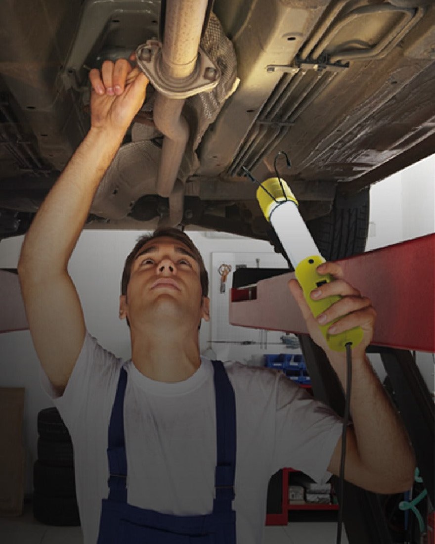 A technician working under a vehicle with a Prime work light